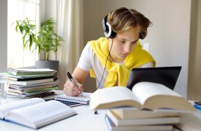 Tennager boy study at home. Online education and distance learning for children. School boy doing his physics homework using gadgets. Lectures and lessons on the internet for high school students